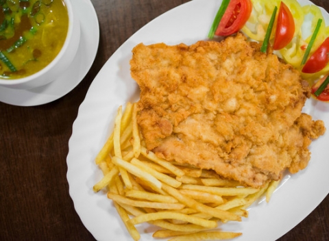 Vyprážaný bravčový rezeň s hranolkami a zeleninovou oblohou a polievkou.