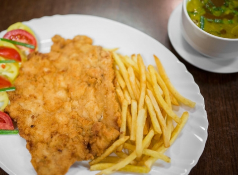 Vyprážaný bravčový rezeň s hranolkami a zeleninovou oblohou a polievkou.