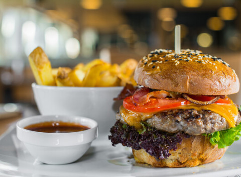 Hovädzí burger v domácej žemli so steakovými hranolkami v bistre na jednotku.